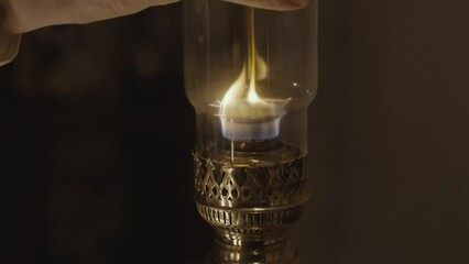 Kerosene lamp. A burning candle on the background of a kerosene lamp. Festive arrival. Beautiful handmade candles. Cozy atmosphere in the house. Old times