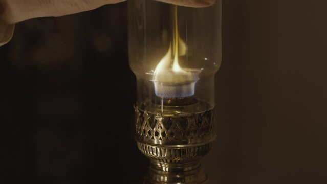 Kerosene lamp. A burning candle on the background of a kerosene lamp. Festive arrival. Beautiful handmade candles. Cozy atmosphere in the house. Old times