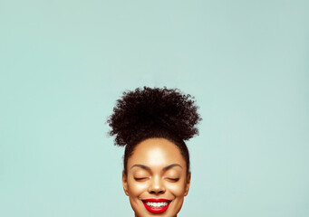 Cropped portrait of a young beautiful African American model with bun hair and closed eyes, smiling...