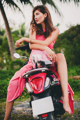 Fototapeta na wymiar young stylish sexy beautiful woman in pink dress on scooter motorbike tropical vacation