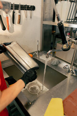 close-up of woman washing dirty dishes in the kitchen after using professional equipment