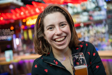 Young woman enjoying an alcoholic drink in a popular bar. Laughing having fun with friends