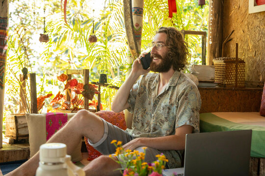 Young Man, a traveller, a digital nomad talks on his phone in a restaurant in Northern Thailand