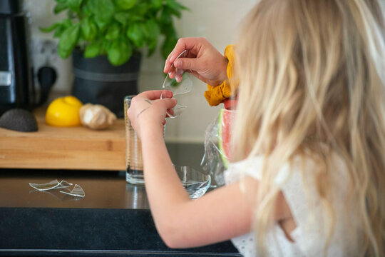 young girl safely putting a broken glass away.