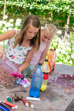 Young girls outside making water bombs with colour paint, fun activities bonding together
