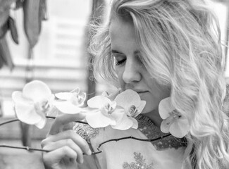 Black and white banner with the face of a beautiful young girl near an orchid. Spring. Beauty concept.