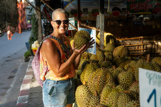 Mid aged woman solo traveller is looking at the local fruit and vegetables in a market in Northern Thailand.