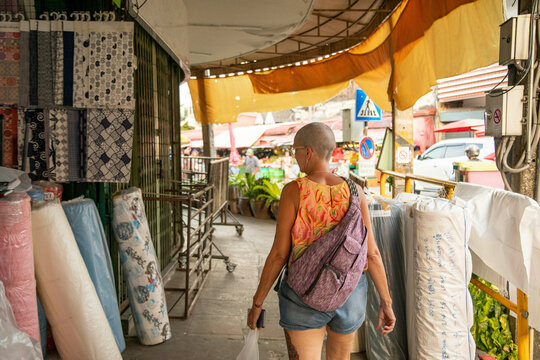 Mid aged woman solo traveller wanders around the local streets, exploring the material shops of Northern Thailand