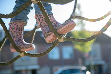 Little girl being brave climbing through a adventure playground in public park