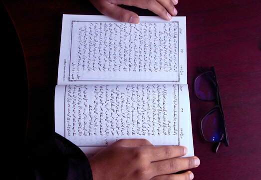 A boy read an Urdu historical book of Islam. urdu manuscript book study concept. book with glass educational concept.