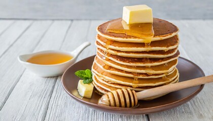 stack of pancakes with butter and honey on white background
