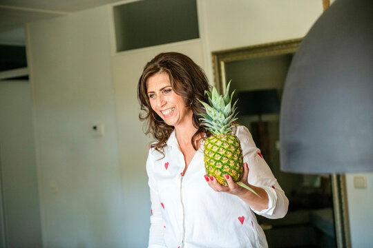 Beautiful brunette older woman carryign a pineapple