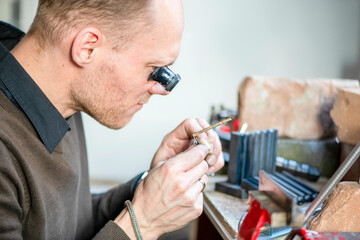 Watch maker repairing a classic watch, authentic work place. Using a monocle and small tiny tools for repairs