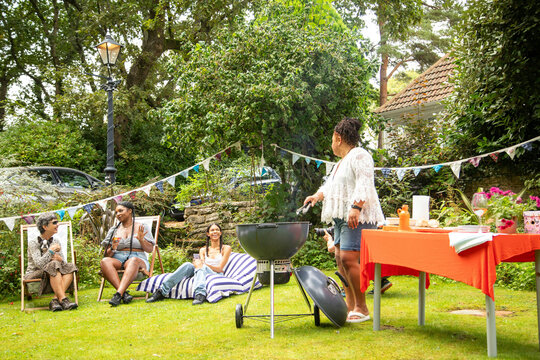 Mixed group of female friends and family gathering to have fun and  enjoy a summer BBQ garden party .