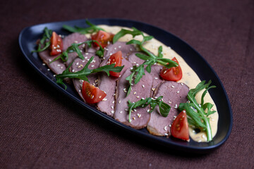 Duck breast with arugula, cherry tomatoes, and sesame seeds on a creamy sauce