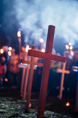 wood cross in rain with crowd holding torches in background