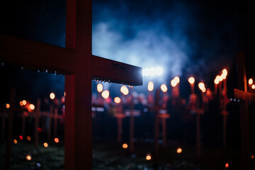 wood cross in rain with crowd holding torches in background