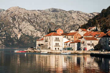Fototapeta na wymiar Perast. Panorama view of the historic town at famous Bay of Kotor with boats in early morning. Mountains at background. Perast, Boka Kotorska, Montenegro