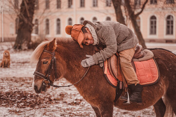 little rider hugs pony and smiles while riding pony