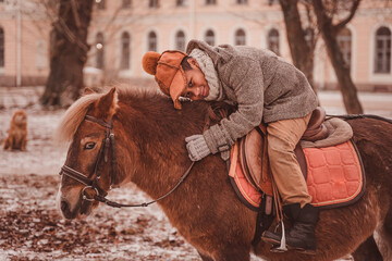 little rider leans towards pony's neck while riding pony