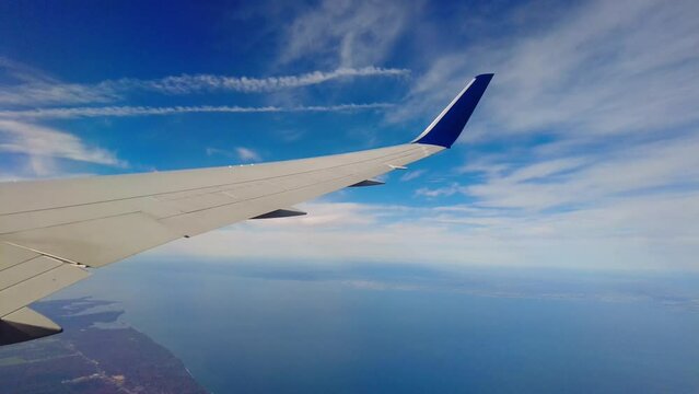 Airplane wing view banking turning revealing coastline seaside land countryside