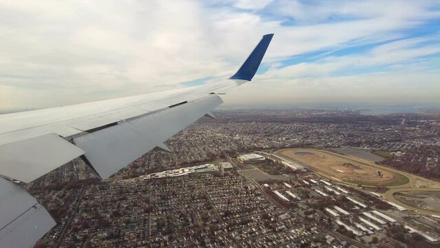 Aircraft low altitude final approach into airport flying over city town urban area landscape arriving flaps extended