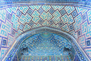 Muqarnas or honeycomb vaulting in iwan entrance to the Ulugh Beg Madrasah at Registan square. Multicolored majolica. Q'ran text (Holy book for muslims) as part of ornament. Samarkand, Uzbekistan