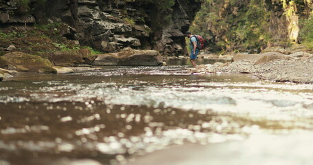 Active tourist man walks along a rocky gorge with a mountain river. Active recreation in the mountains.