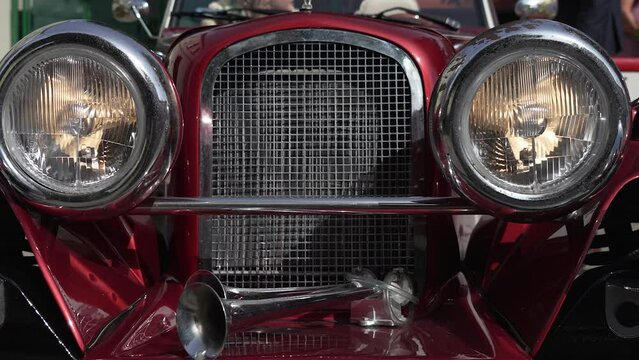 Old vintage car. Muscle american auto front bumper headlight and grill. Red convertible cabriolet vehicle. Closeup headlight and front side of vintage cars. Old fashioned polished shiny auto. Details