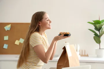 Fotobehang Happy young woman with sushi and paper bag in kitchen © Pixel-Shot