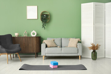 Interior of living room with sofa, armchair and yoga equipment
