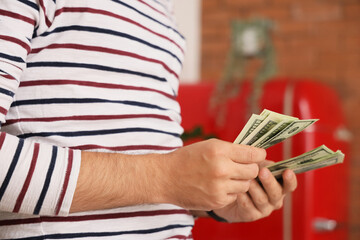 Young man counting money in kitchen, closeup