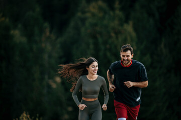 Naklejka premium Fit couple jogging amidst a scenic mountain landscape, dressed in sporty attire