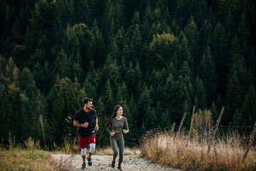 Fit diverse couple jogging amidst a scenic mountain landscape