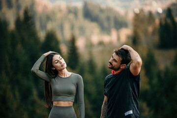 Couple stretching and sharing a moment before their mountain trail run in matching workout clothes