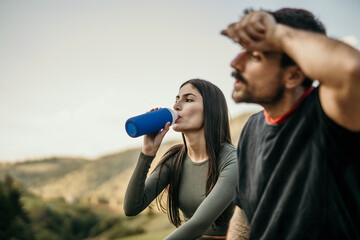 Multicultural friends take a breather after jogging, discussing their workout and drinking a water