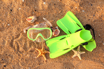 New swimming mask, flippers, starfishes and seashells on sand