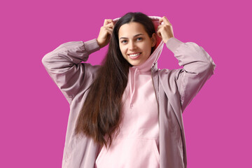 Young woman in jacket and hoodie on purple background