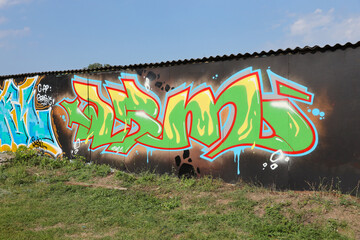 The old wall decorated with paint stains in the style of street art culture. Colorful background of full graffiti painting artwork with bright aerosol outlines on wall. Colored background texture