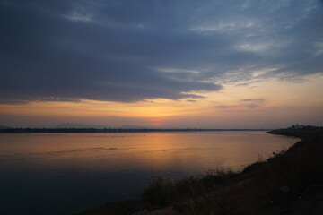 Fototapeta na wymiar The orange glow of the sunset along the beautiful river