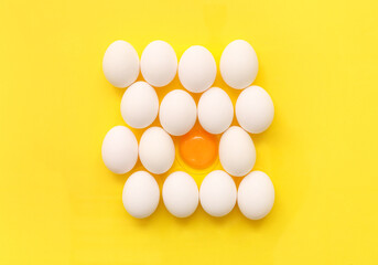 Cracked and whole chicken eggs on yellow background