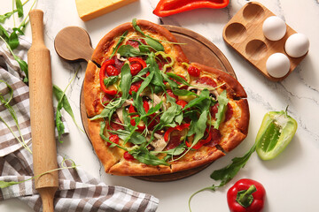 Wooden board with tasty heart shaped pizza and ingredients on white background