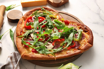 Wooden board with tasty heart shaped pizza on white background