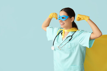 Beautiful female doctor in superhero costume showing muscles on blue background