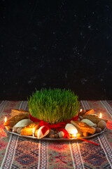 Beautiful Novruz tray on rug with semeni - wheat grass, pakhlava, shekerbura and festive candles on...