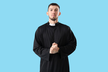 Young priest on blue background