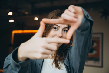 A stylish young woman with blue eyes and freckles on her face, and with a nose piercing and a blue...
