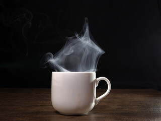 Smoke vape fog flowing out of white ceramic coffee cup on dark black background