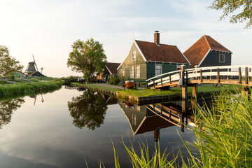 Fototapeta na wymiar Beautiful village of Zaanse Schans in Netherlands at sunset with the wooden houses and the bridge reflected on the canal in a sunny day. Netherlands.