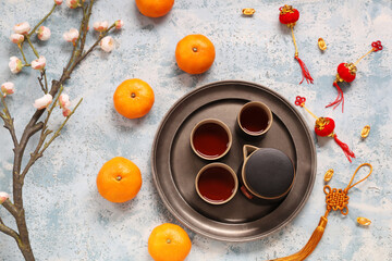 Cups of tea with mandarins, sakura branch and Chinese symbols on blue grunge background. New Year celebration